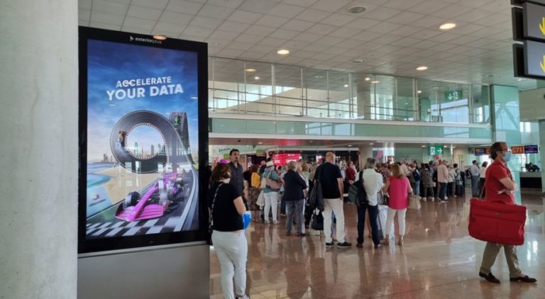 At Barcelona Airport Terminal 1, many people can be seen. On the left side there is a digital City Light Poster displaying product advertising for Ataccama Software.