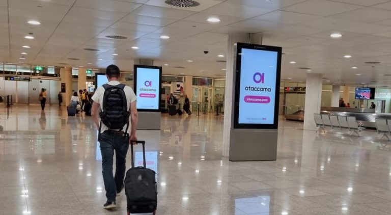 In the waiting area at Barcelona Airport, people are visible on the left and in the background of the image. Three digital City Light Posters are lined up in a row, showing advertising for Ataccama Software.