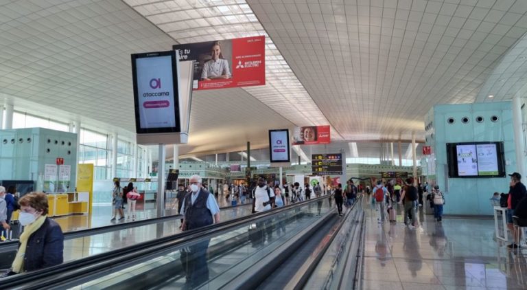 At Barcelona Airport Terminal 1, there are many people around the escalator. Two digital City Light Posters are in a row, and the digital screen displays product advertising for Ataccama Software.