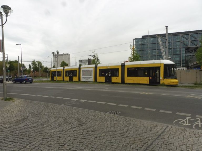 A tram with carriages displaying advertising from the software company Asana in the form of Traffic Boards. The tram is moving on the median of a street.