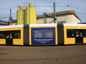 a tram with an image ad on the side for "Asana"