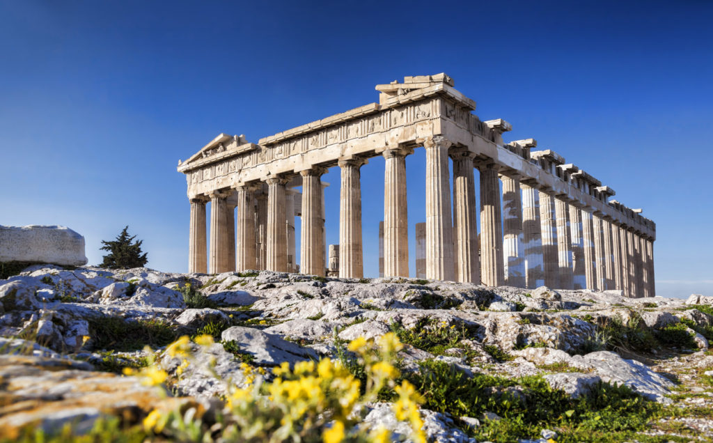 The picture shows the landmark 'Acropolis' in Athens. In the foreground, there are flowers