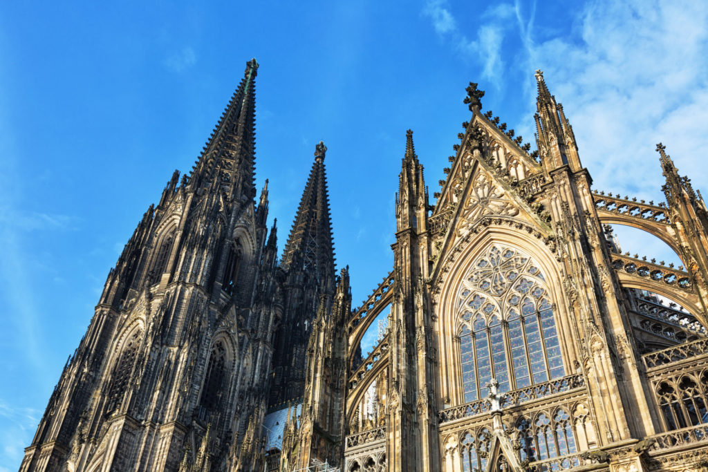 The picture shows the landmark 'Cologne Cathedral' in Cologne. In the foreground, there are trees.