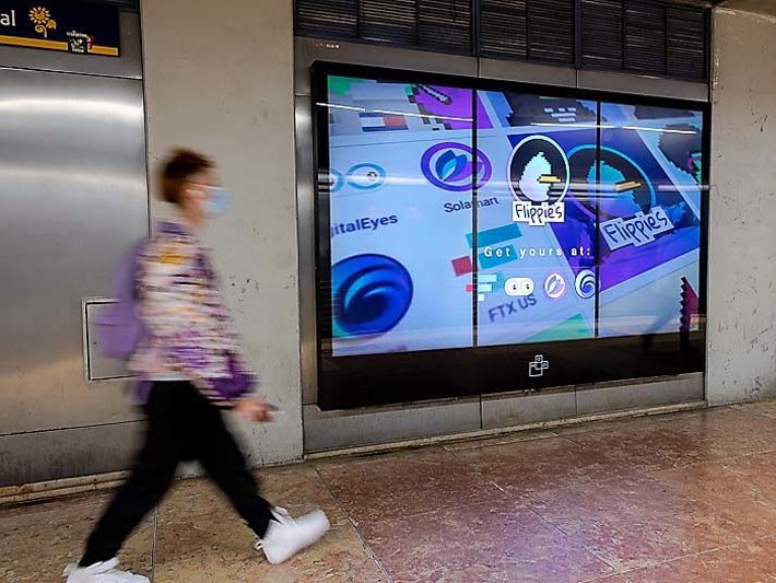 Advertising on a digital billboard for 'Flippies Art,' with a pedestrian crossing the image.