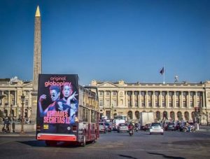 In Paris, in front of the Place de la Concorde, a sightseeing bus with Super Rear advertising is visible. The design belongs to Globoplay Originals.