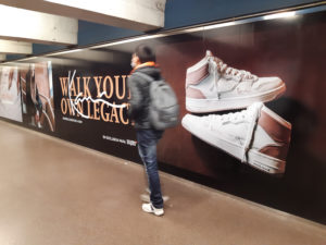 Snipes advertisement in a tunnel. A pedestrian is walking through the frame.