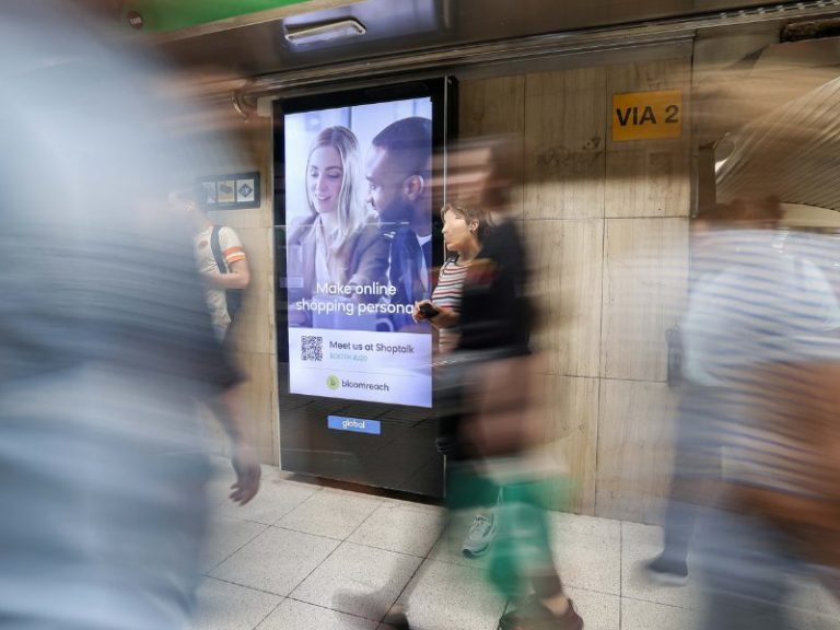 Digital billboard advertising, passers-by walk by.