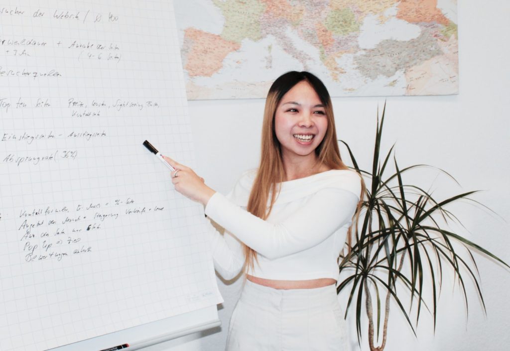 Celine Pham works for wtm-outdoor-advertising. Smiling face while presenting key facts on a whiteboard.