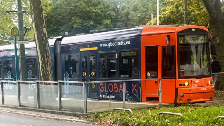 The image features a tram at a station, showcasing an advertisement for Global X Management.