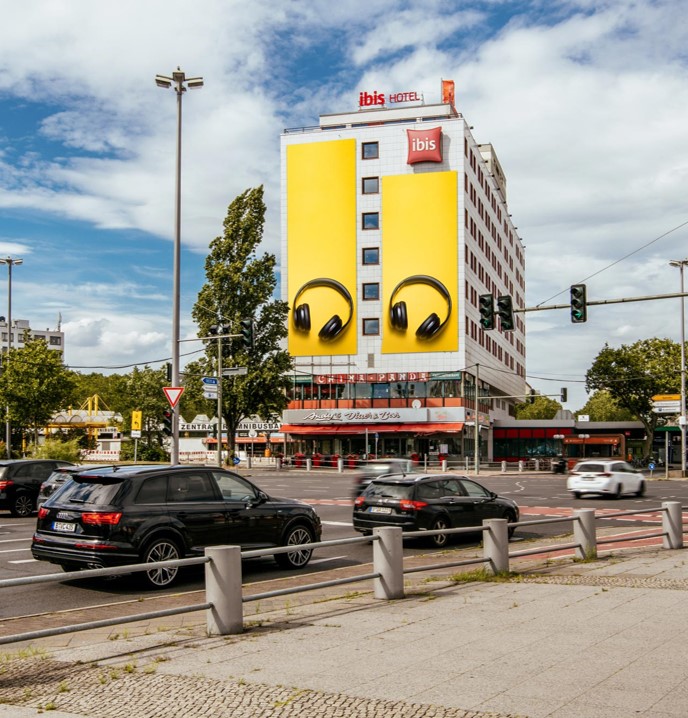 cars in ftont of the ibis hotel with advertising on the side wall