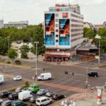 Busy road with a giant poster, hanging on a wall, close to Messe Berlin