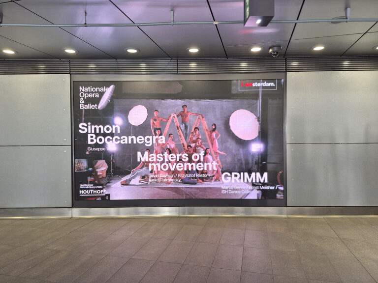 A large-format digital screen at the Europaplein subway station at the RAI Amsterdam. It displays outdoor advertising for a dance performance in Amsterdam.