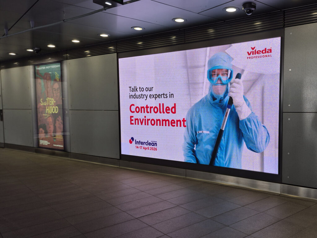 A large digital screen at RAI Amsterdam metro station. The screen shows advertisement from the company Vileda, promoting their presence at Interclean trade fair. On the left, there is a digital City Light Poster.