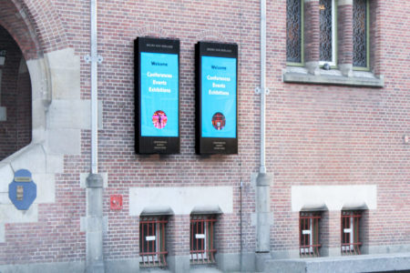 On a building in Amsterdam, two digital City Light posters are placed on the facade.