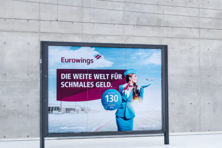 Eurowings advertising is presented on a very large and freestanding City Light board. The striking advertising display is located on the railway platform at the airport in Cologne.