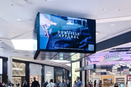 A digital billboard screen in a shopping center in Copenhagen displays advertising for jeans produced by 'Dunville Apparel'