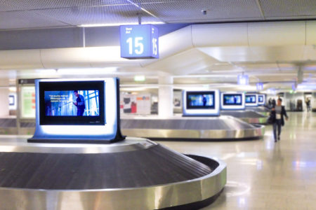 In the baggage claim area at Frankfurt am Main Airport, there are five digital screens right next to the baggage pickup.