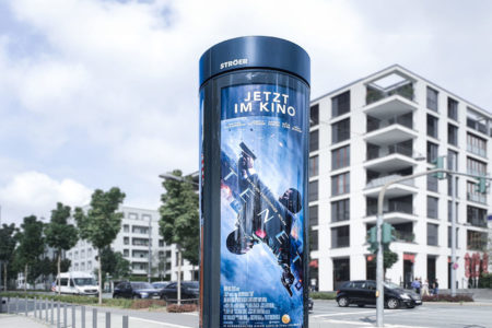 A City Light column next to a street in Frankfurt am Main promotes the movie 'Tenet