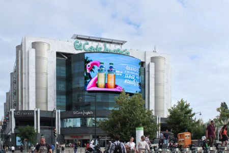 On the 'El Corte Inglés' shopping complex in Lisbon, a digital giant poster is hanging on the facade. The digital screen displays an advertisement for 'Aquarius' beverages.