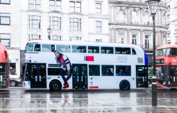 A bus in London is covered with a full design, advertising the 'Tommy Hilfiger' brand.