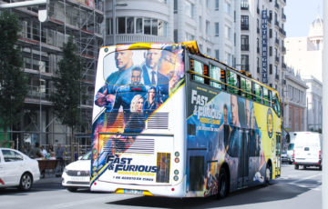 A bus is traveling through Madrid with a full wrap advertising 'Fast & Furious.'