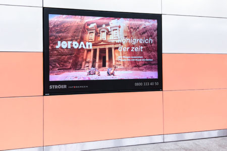 A digital billboard in Munich shows tourism advertising for Jordan.