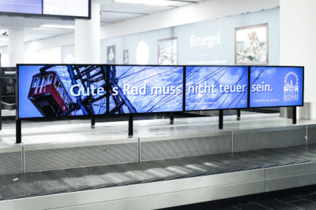 A digital screen at Vienna Airport, located at baggage claim, displays the Vienna Ferris wheel.